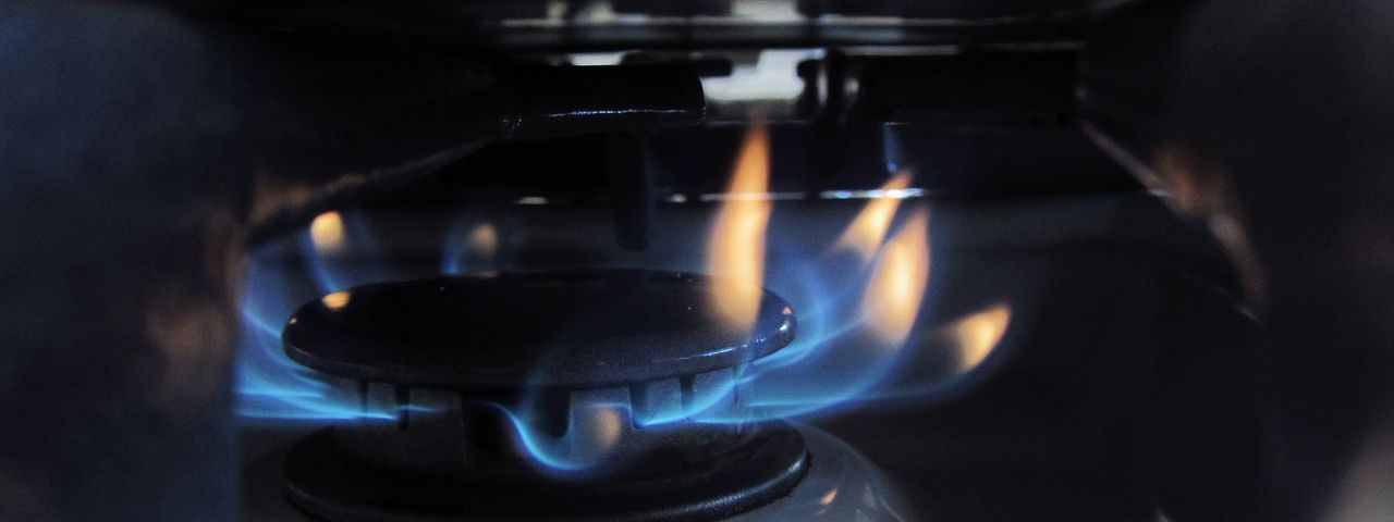 Een blauwe gasvlam op een gasfornuis, van dichtbij